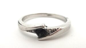 Silberner Ring, besetzt mit einem schwarzen Meteoritenfragment auf weißem Hintergrund