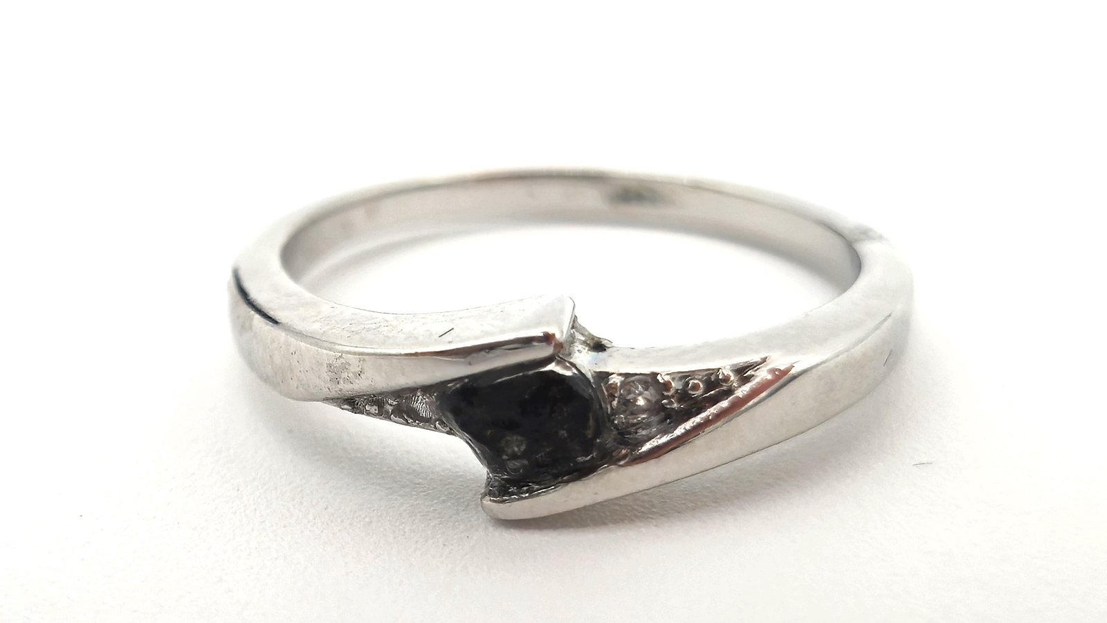 Silberner Ring, besetzt mit einem schwarzen Meteoritenfragment auf weißem Hintergrund